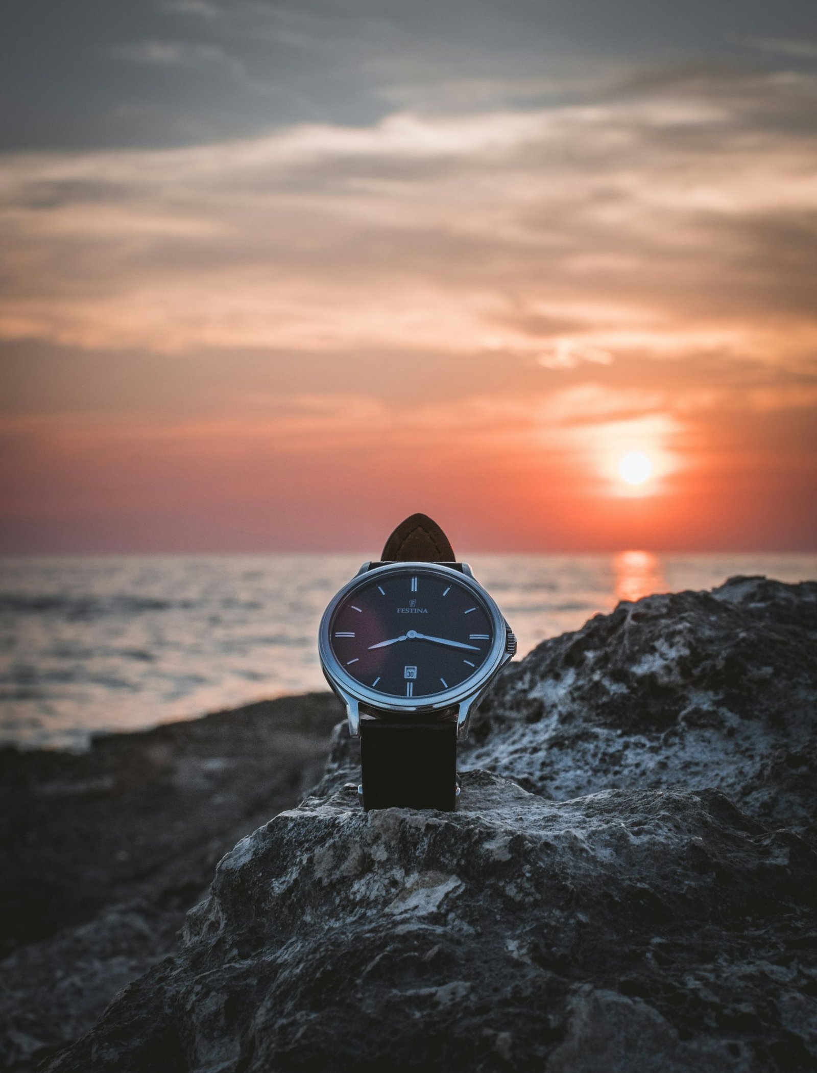 A watch resting on a rock at sunset