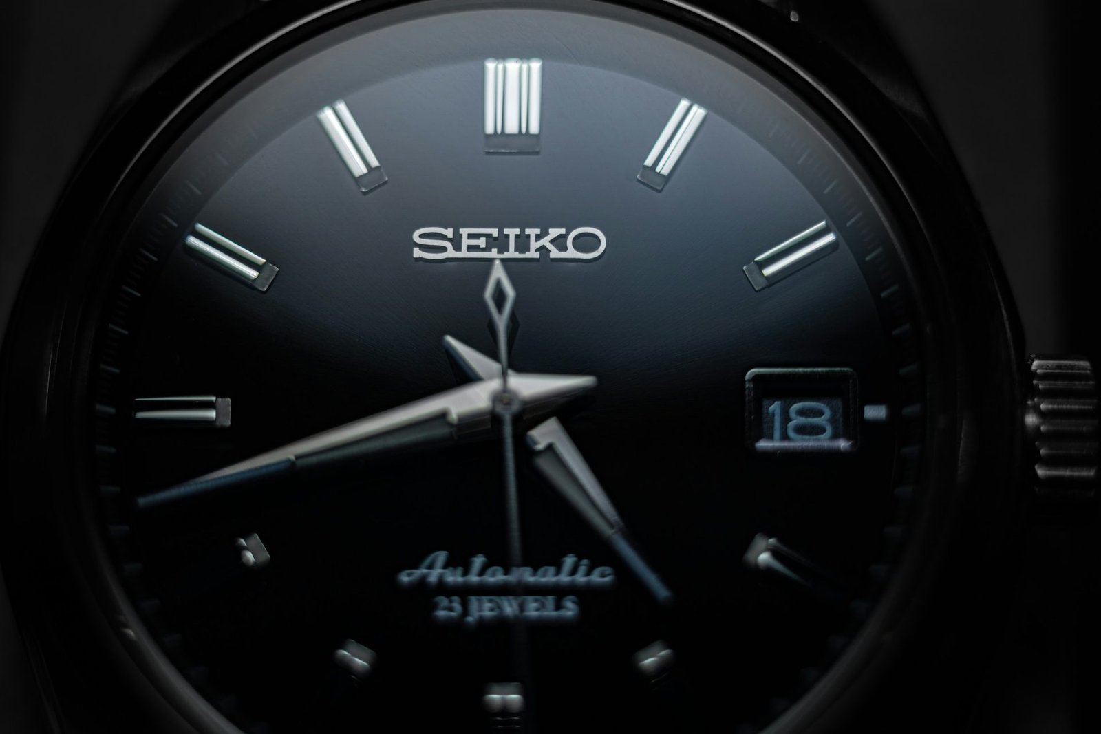 Close-up of a black-dial automatic watch with polished steel hands
