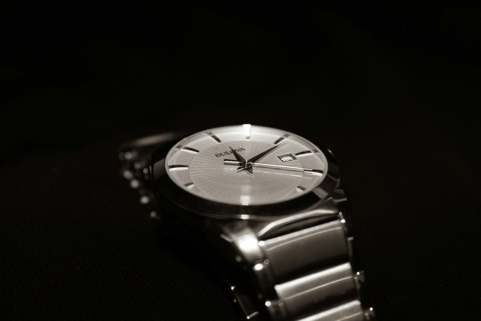 Steel watch with a silver dial and bracelet in low light